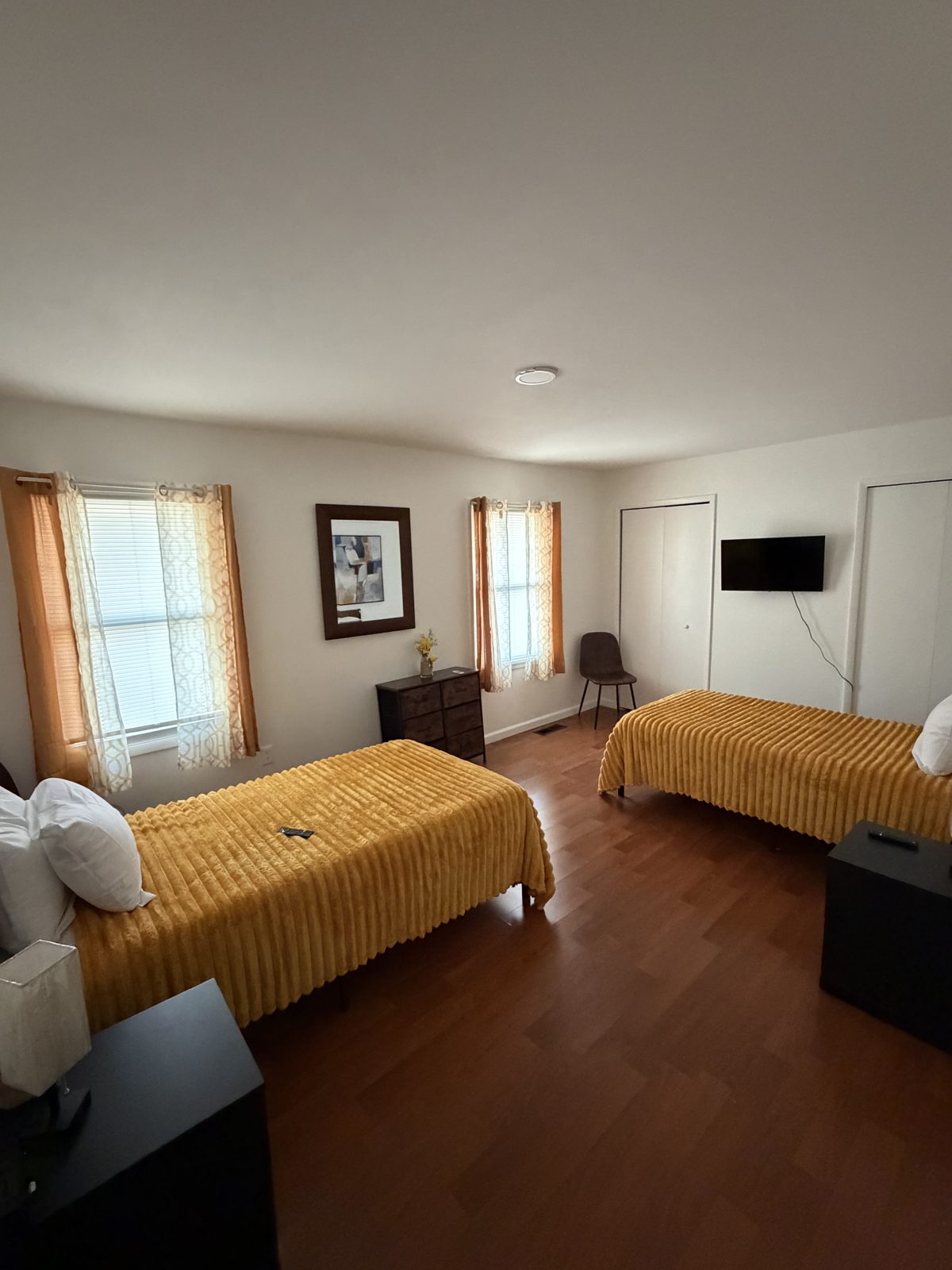 Semi-private room with two twin beds, warm gold bedding and hardwood floors